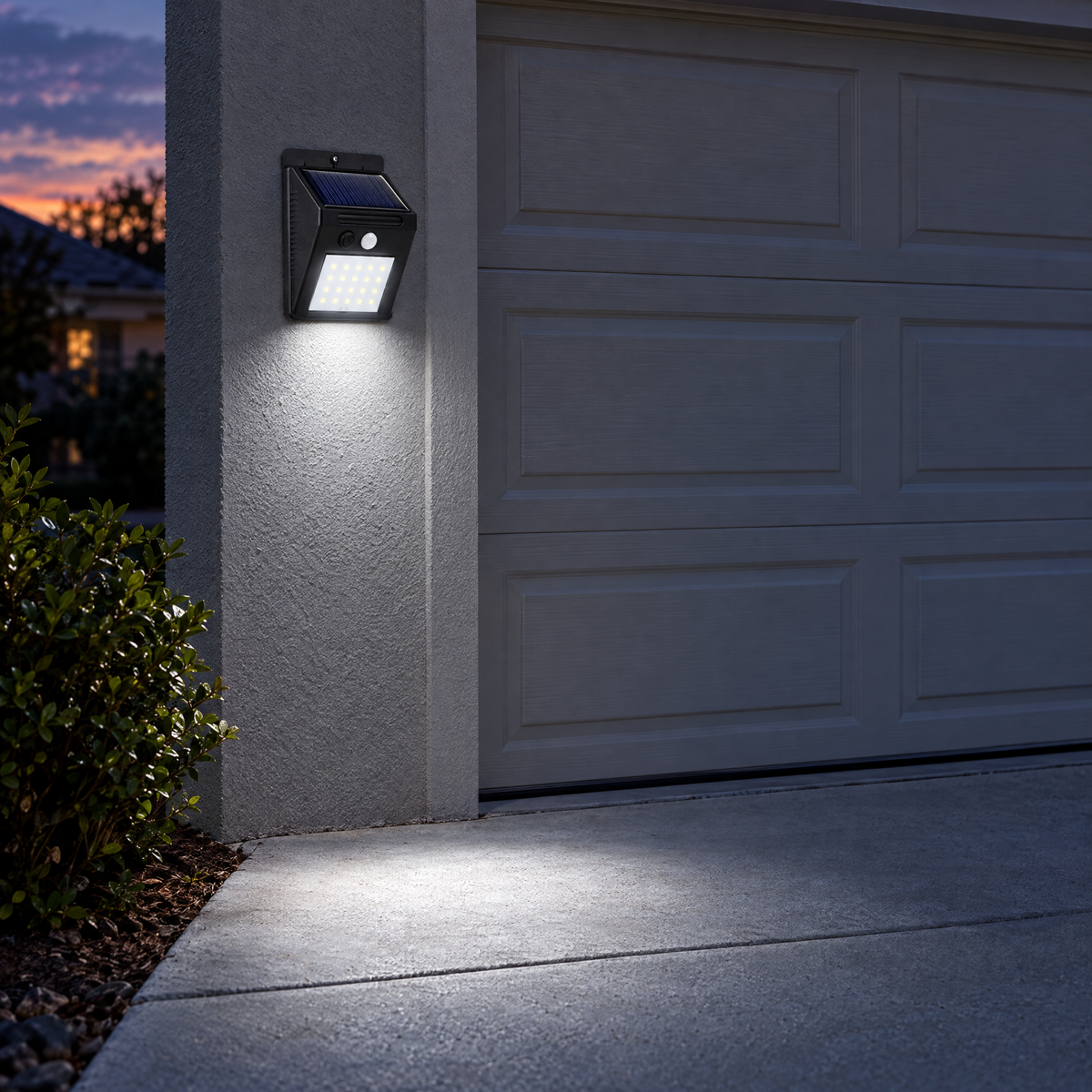 Solar motion sensor light mounted beside a garage door lighting the driveway at dusk