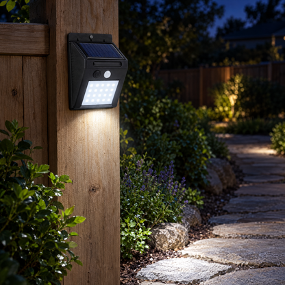Solar motion sensor light on a fence post lighting a garden path at night